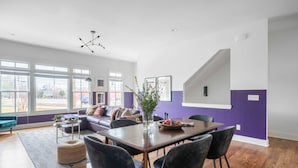 Una sala de estar moderna con comedor, ventanas amplias y una escalera.