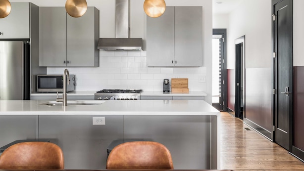 Una cocina moderna con una isla central, electrodomésticos de acero inoxidable e iluminación colgante.