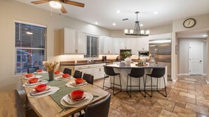 A modern kitchen with white cabinets, a central island with bar stools, a built-in oven, and a stainless steel refrigerator. - Northstar Zen Resort: Rock Waterslide Pool, Spa, MultiBall Zone & Game Room (Glendale)