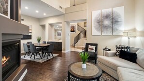 A spacious living area with a fireplace, dining table, and sofas. - Northstar Zen Resort: Rock Waterslide Pool, Spa, MultiBall Zone & Game Room (Glendale)