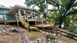 Eine Holzterrasse mit einer Treppe, die zu einer gläsernen Veranda führt.