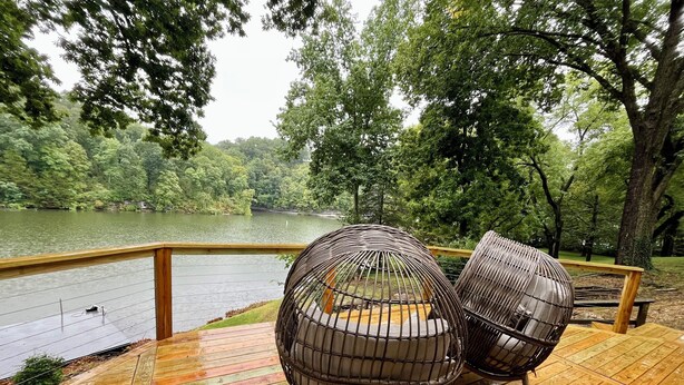 Eine Holzterrasse mit zwei Korbstühlen mit Blick auf einen See.