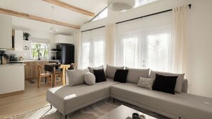 A modern living room with a sectional sofa, a dining area, and a kitchen. - NEW Zen Cabin in the Clouds . Hot Tub, Wineries, Skyline  (Front Royal)