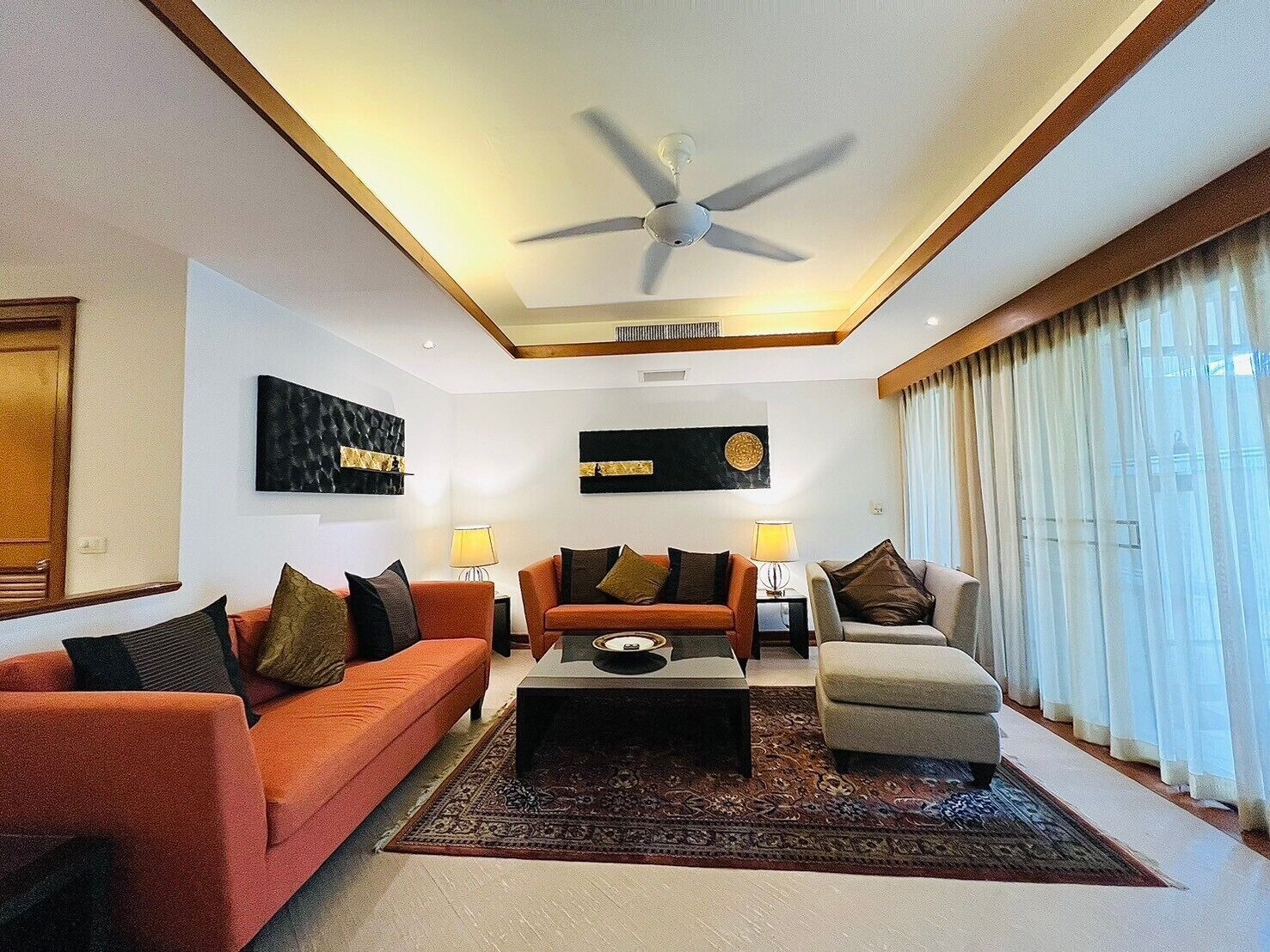 A modern living room with a ceiling fan, two sofas, a coffee table, and a rug.