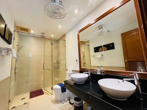 A modern bathroom with a glass-enclosed shower, two sinks, and a large mirror.