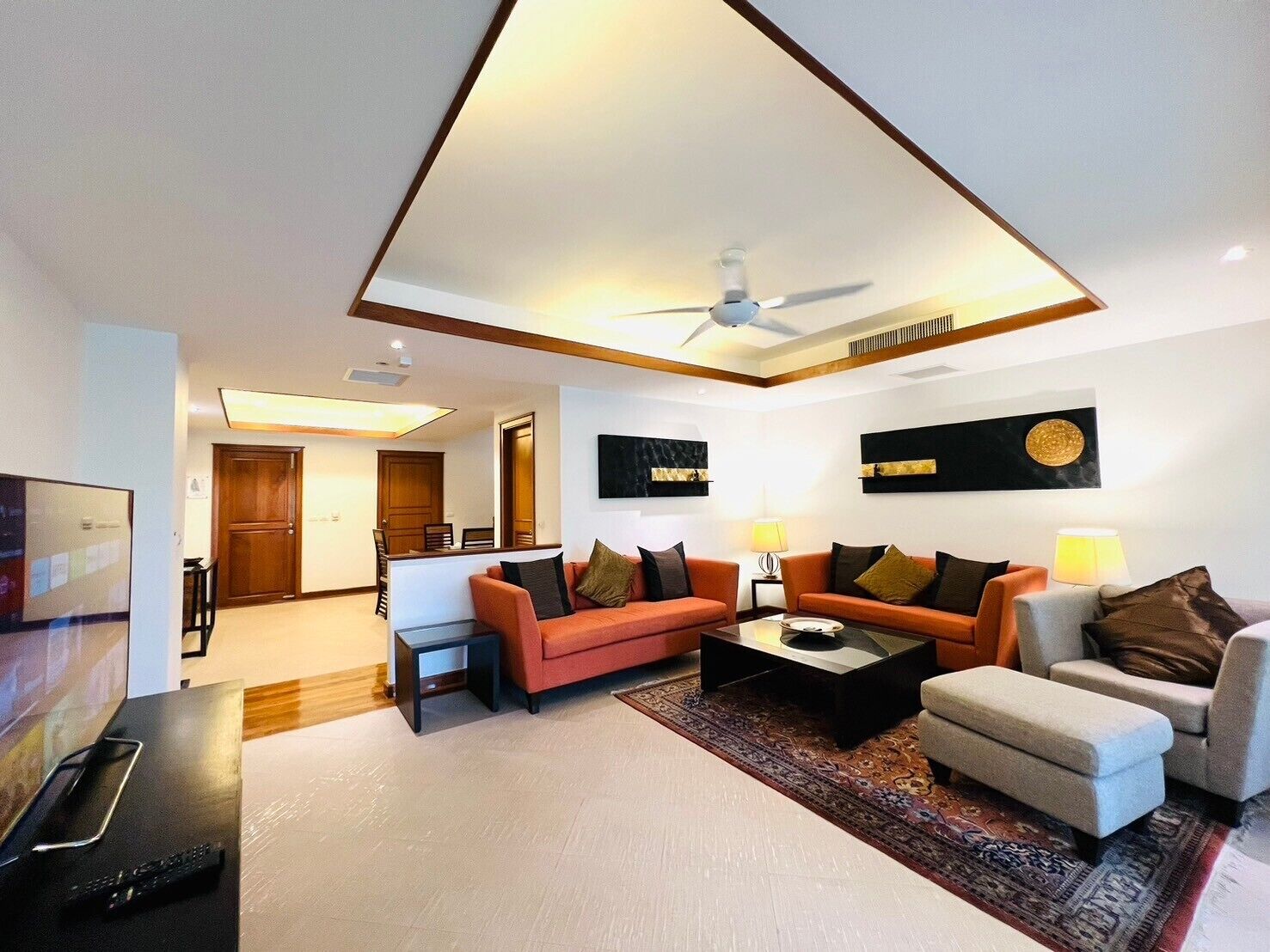 A modern living room with a sofa, armchairs, a coffee table, and a TV.