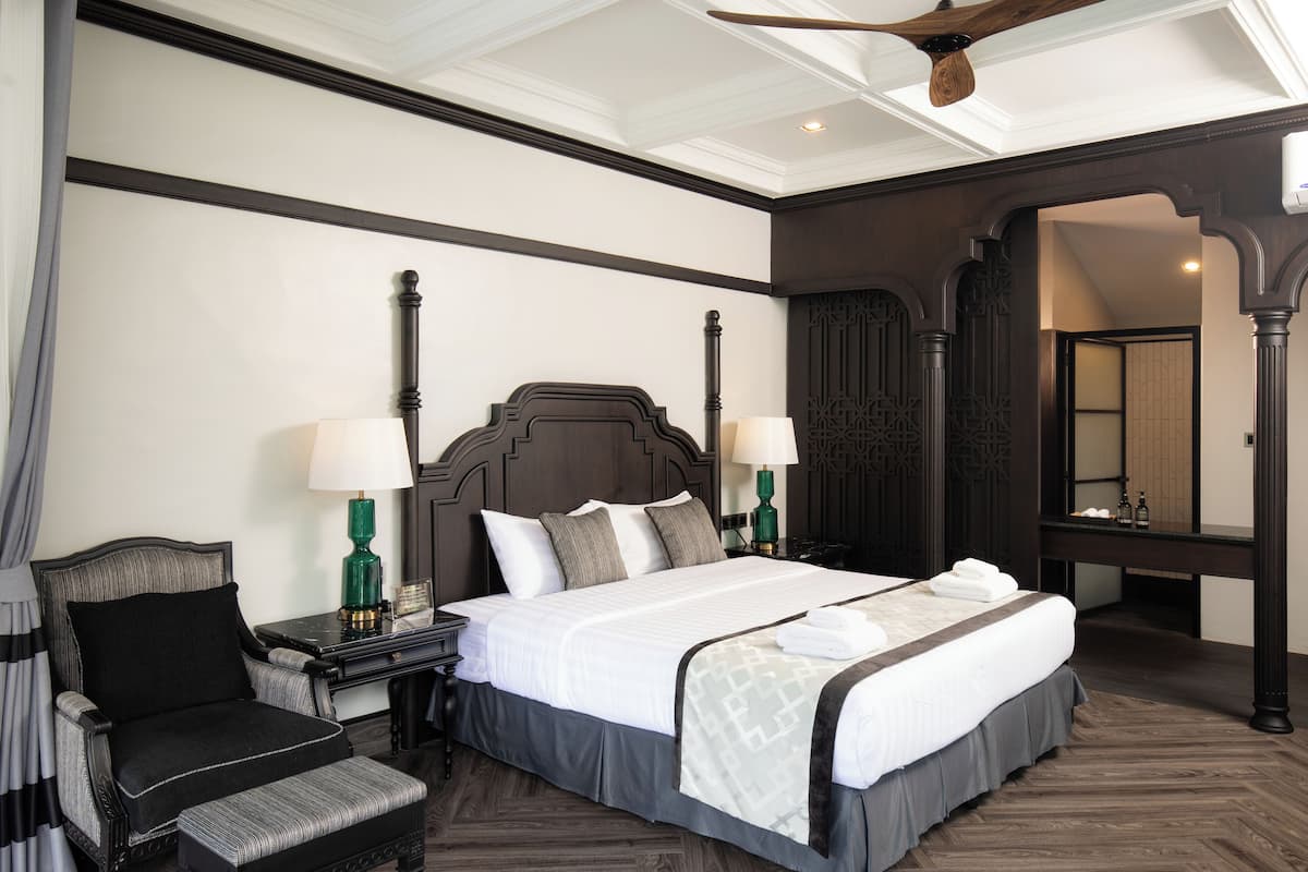 A hotel room with a large bed, two bedside tables with lamps, a chair, and a mirror.