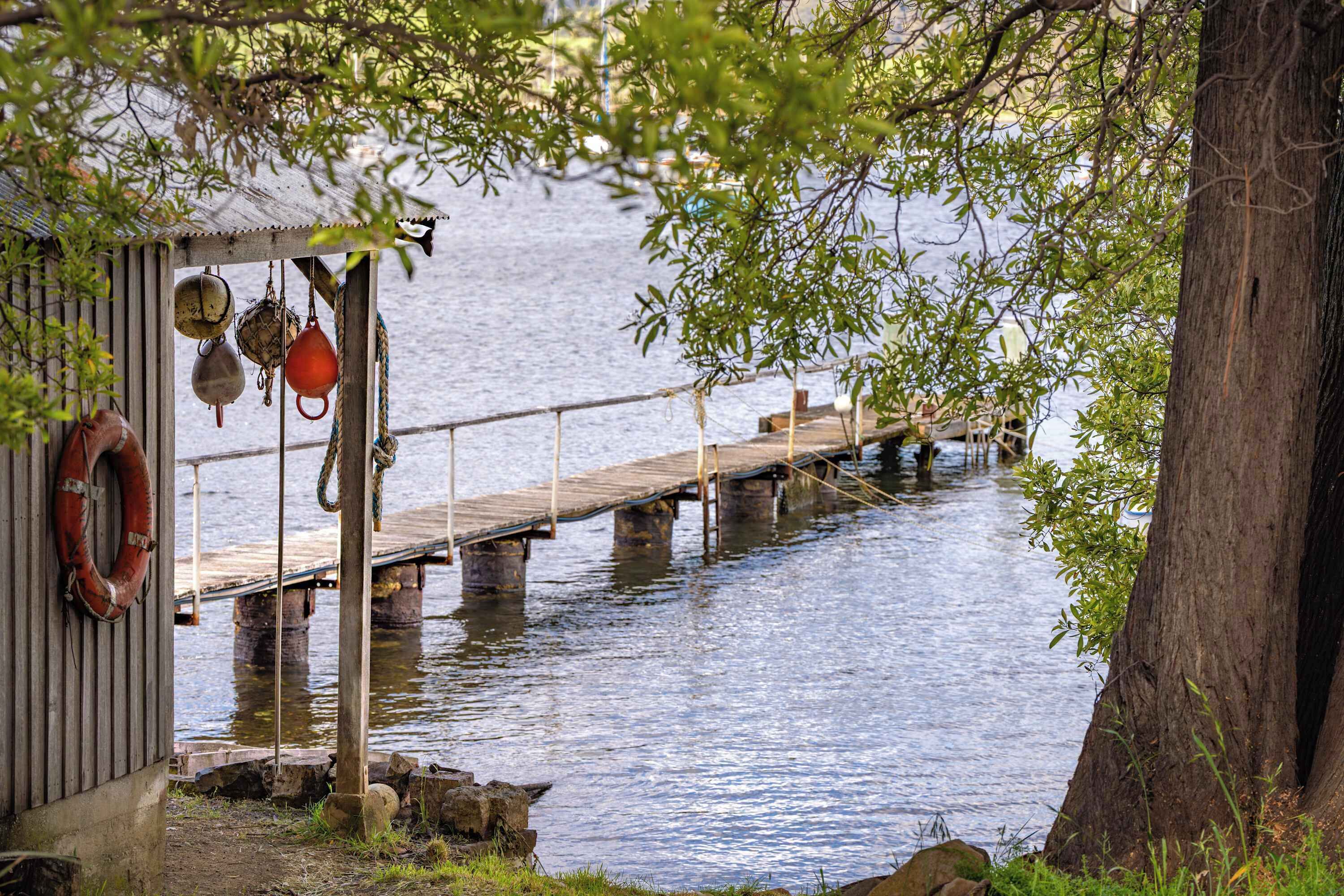 A dock extending into calm water, a wooden pier, and a small building with a lifebuoy hanging.