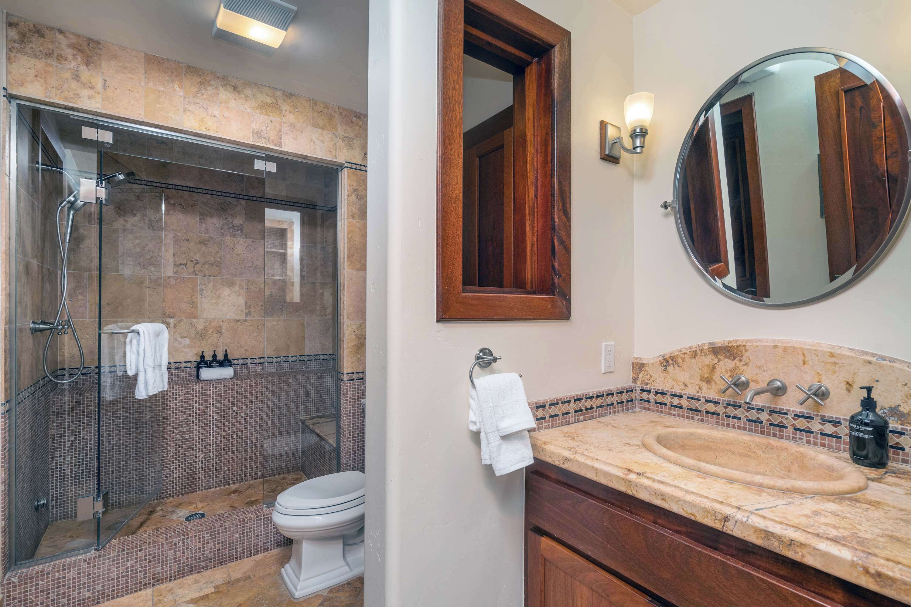 Un bagno con doccia vetrata, un water, un lavandino con specchio e un porta asciugamani.