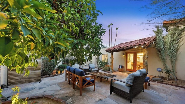 A patio area with outdoor furniture, a fire pit, and a building entrance.