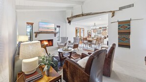 A spacious living room with a fireplace, leather sofas, and a dining area with chairs.