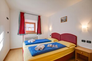 A double bed with blue and yellow bedding, a red headboard, and a small bedside table.