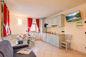A compact living space with a dining area, kitchen, and a sofa with a magazine.