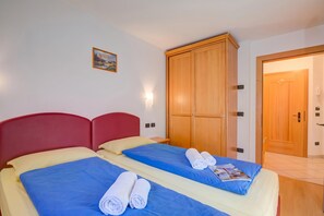 Una habitación de hotel con dos camas, un armario de madera y una puerta.