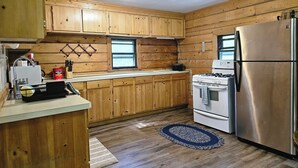 A kitchen with wooden cabinets, a stainless steel refrigerator, a stove, and a window.