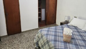 A bedroom with a bed, a wardrobe, and a bedside table with a lamp.
