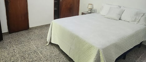 A bedroom with a bed, a nightstand, a lamp, and a painting on the wall.