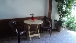 A small round table with two chairs, a potted plant, and a wall with a brick pattern.