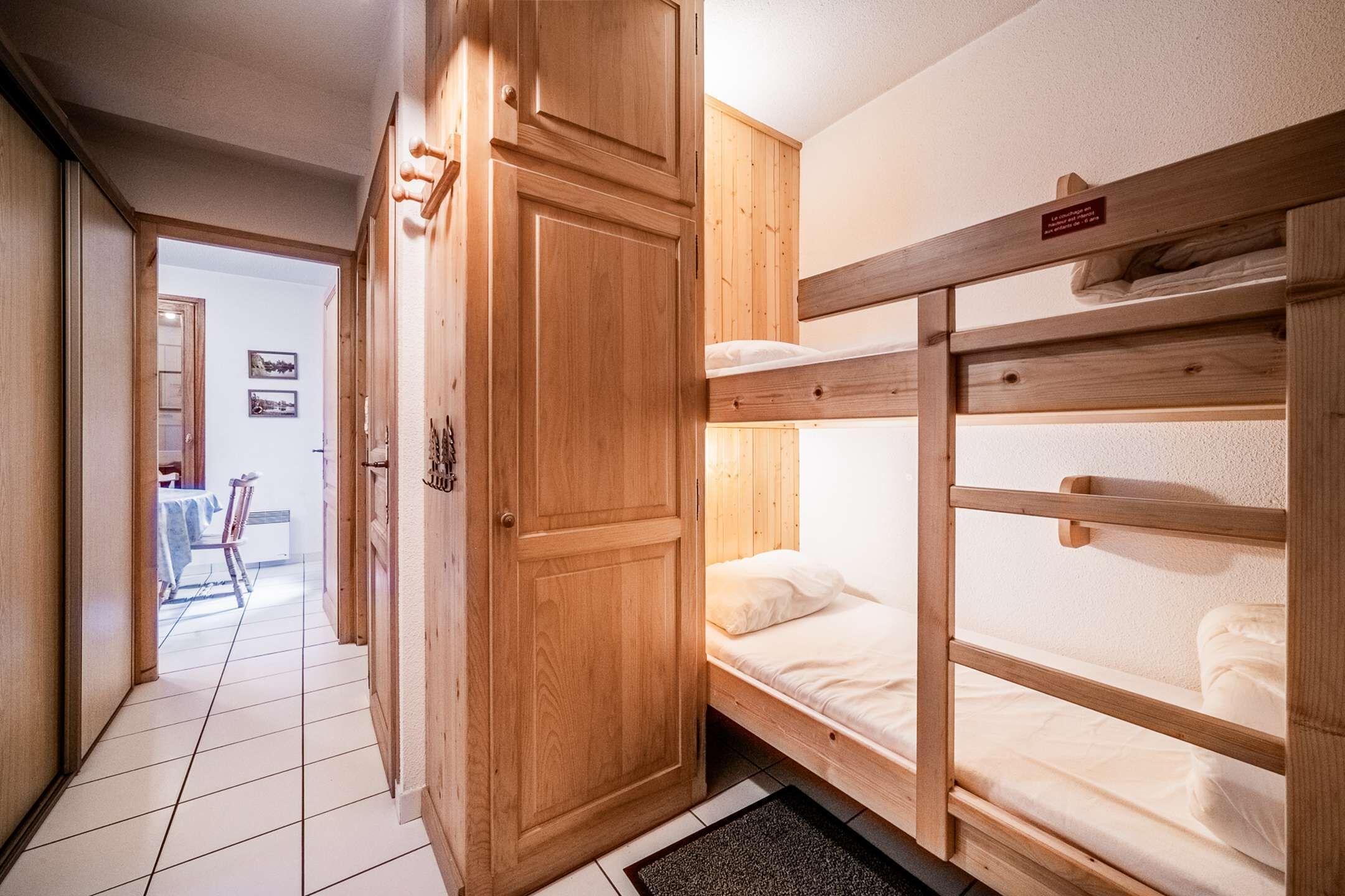 A wooden bunk bed room with a door and a small table in the background.