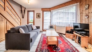 A living room with a sofa, coffee table, TV, and speakers.