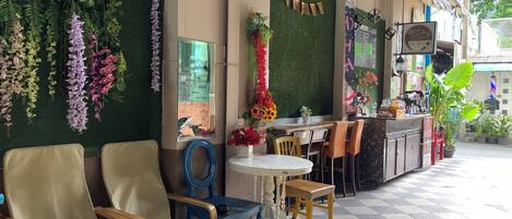 A cafe with seating, a counter, and decorative plants.