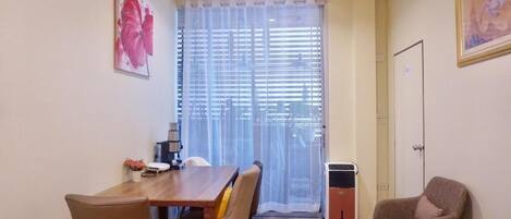 A room with a dining table, chairs, a sofa, a heater, and a door.