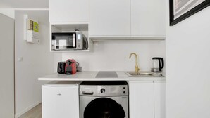 A compact kitchen with a built-in microwave, a coffee maker, and a washing machine. - Intimate Apartment - 2P - Le Marais (Paris)