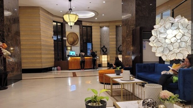 Un vestíbulo moderno con una recepción, zona de estar y detalles decorativos.