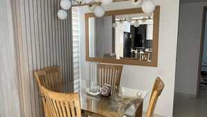 Spiseområde med et glasbord, træstole og en moderne pendel.