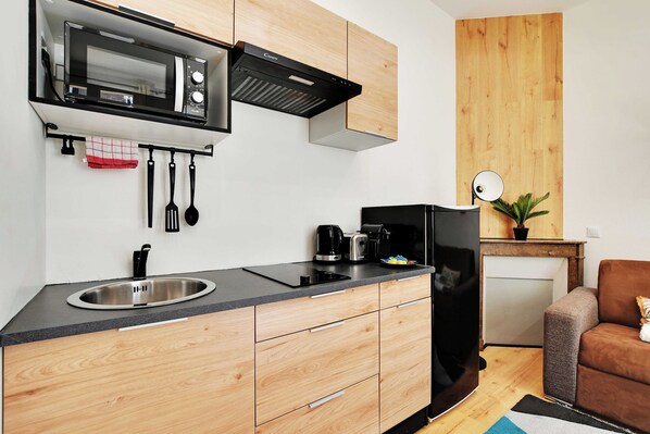 Una cocina compacta con microondas, estufa, lavaplatos y armarios de madera.