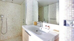 Een badkamer met een grote spiegel, een wastafel en een douche.