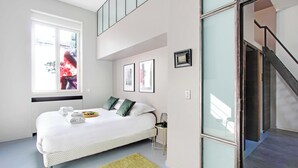 Een moderne slaapkamer met een bed, een raam, een klein tafeltje en een trap.