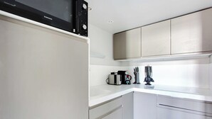 Een moderne keuken met roestvrijstalen apparatuur, witte kasten en een aanrecht met een koffiezetapparaat en keukengerei.