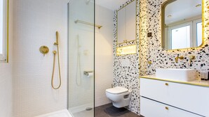 A modern bathroom with a glass shower enclosure, a white toilet, and a vanity with a speckled backsplash.