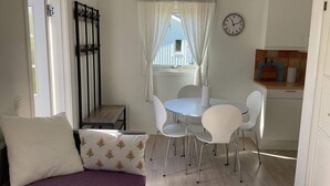 A compact room with a bed, a dining table with chairs, a kitchen area, and a clock on the wall. - 4 Star Holiday Home in Falkenberg (Falkenberg)
