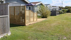 A row of mobile homes with a grassy yard and a wooden fence. - 4 Star Holiday Home in Falkenberg (Falkenberg)