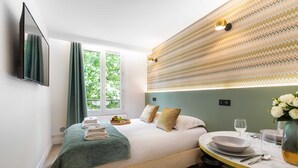 Ein Hotelzimmer mit Bett, Esstisch und Blick auf Grünfläche.