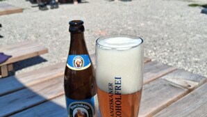 Une bouteille et un verre de bière sur une table en bois, dans un endroit situé au bord de la plage.