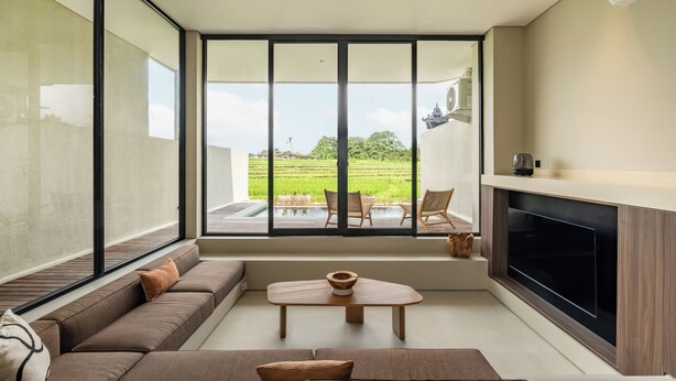 A modern kitchen with a large window, a built-in oven, and a seating area with a sofa and a table. - Villa Mesra Stunning Paddy Fields Views - Canggu Berawa (Bali)