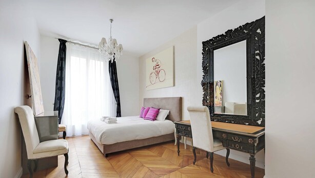 A bedroom with a bed, a desk, a chair, a large mirror, and artwork on the wall. - Charming 2br/4p - Georges V / Champs-elysees (Paris)