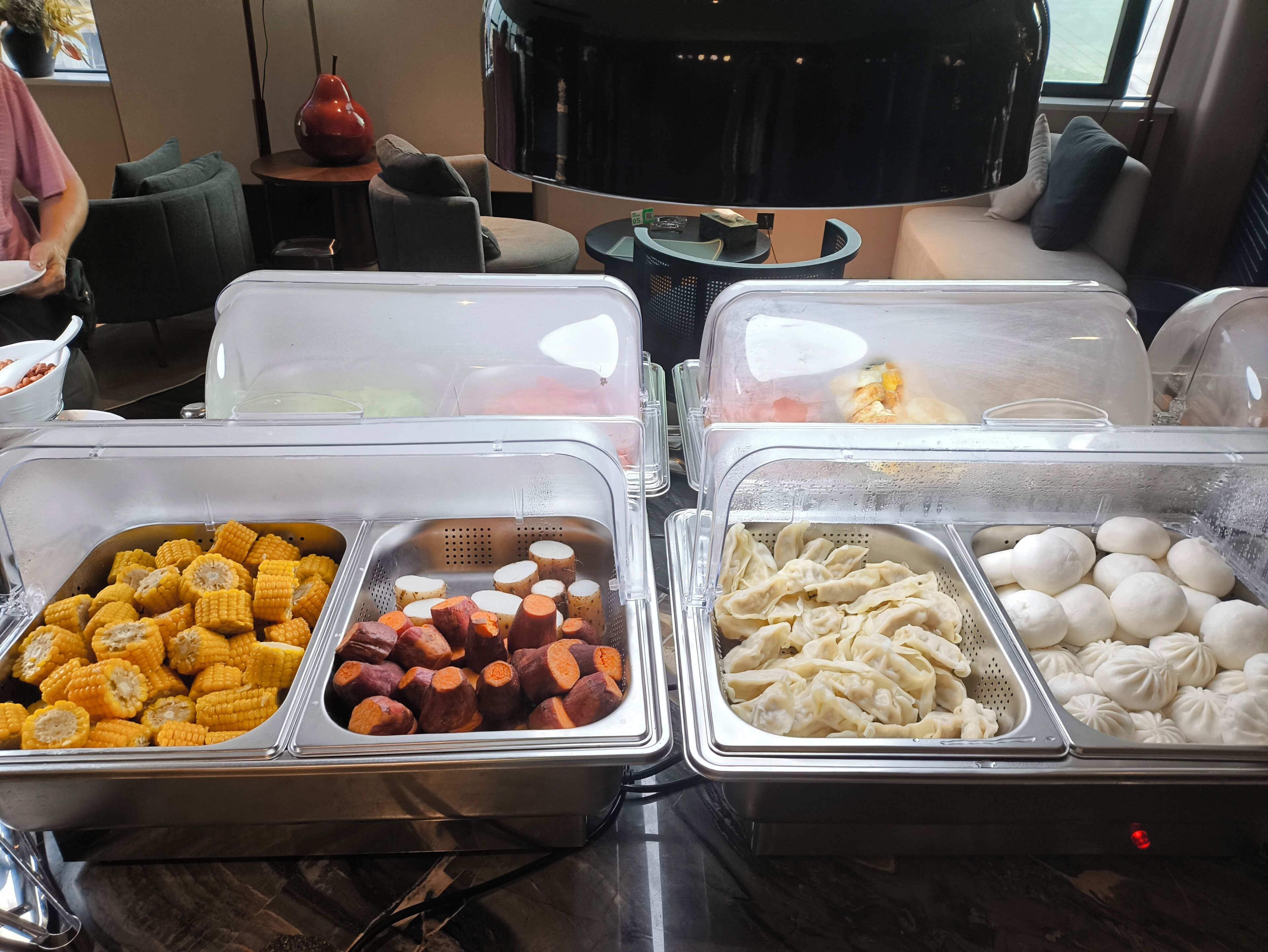 A buffet with various food items including corn, sweet potatoes, dumplings, and eggs.