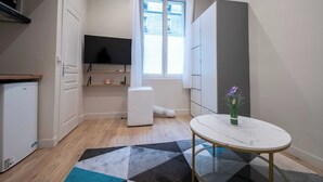 A compact kitchen with a built-in TV, a small fridge, and a window with curtains.