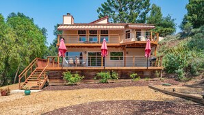 A two-story log cabin with a deck, outdoor seating, and a staircase.
