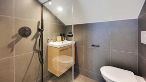 Une salle de bain moderne avec une douche à parois de verre, un meuble-lavabo en bois et des toilettes blanches.