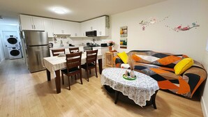 Espaço compacto com área de refeições, cozinha compacta e sofá com almofadas coloridas.