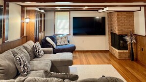 Ein Wohnzimmer mit einer Eckcouch, einem Kamin und einem großen Fenster.