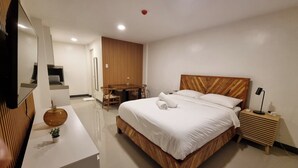 A modern hotel room with a wooden bed, a desk, a chair, a small table with a vase, and a television. - Flat 35  (Las Piñas)