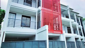 A multi-story residential building with a modern design, featuring balconies and a prominent red vertical structure. - Flat 35  (Las Piñas)