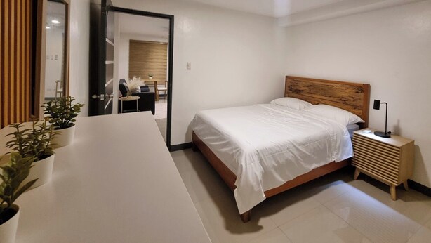 A modern bedroom with a large bed, bedside table, and a mirror. - Flat 35  (Las Piñas)