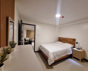 A modern bedroom with a large bed, bedside table, and a mirror. - Flat 35  (Las Piñas)